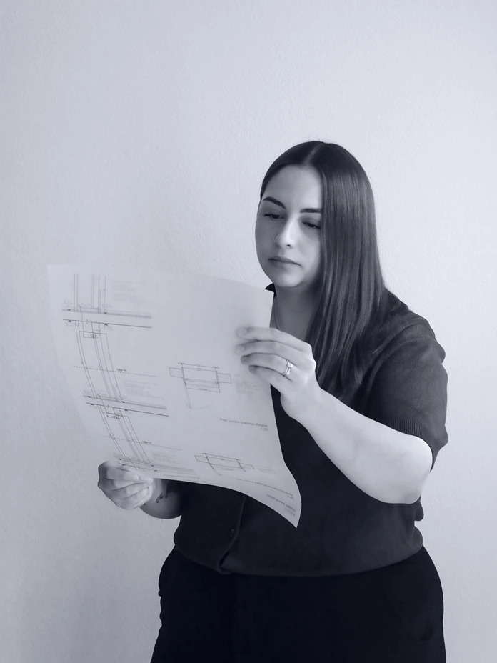 Dessinatrice en architecture de Logibat analysant des plans de construction pour un projet immobilier en Suisse romande.