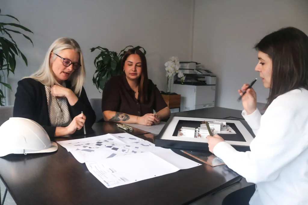 Équipe Logibat analysant des plans et une maquette pour un projet immobilier en Suisse romande.
